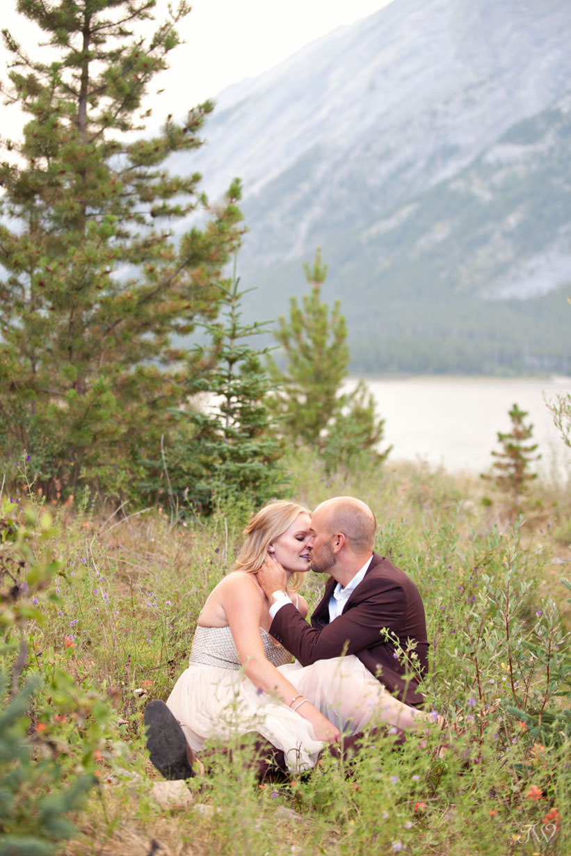 Caitie and Mark sit in the wildflowers at their Spray Lakes engagement session captured by Tara Whittaker Photography